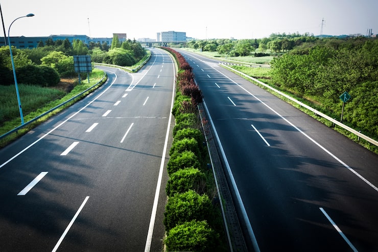 Illustration of a multi-lane expressway cutting through green land, representing the Ahmedabad-Dholera Expressway